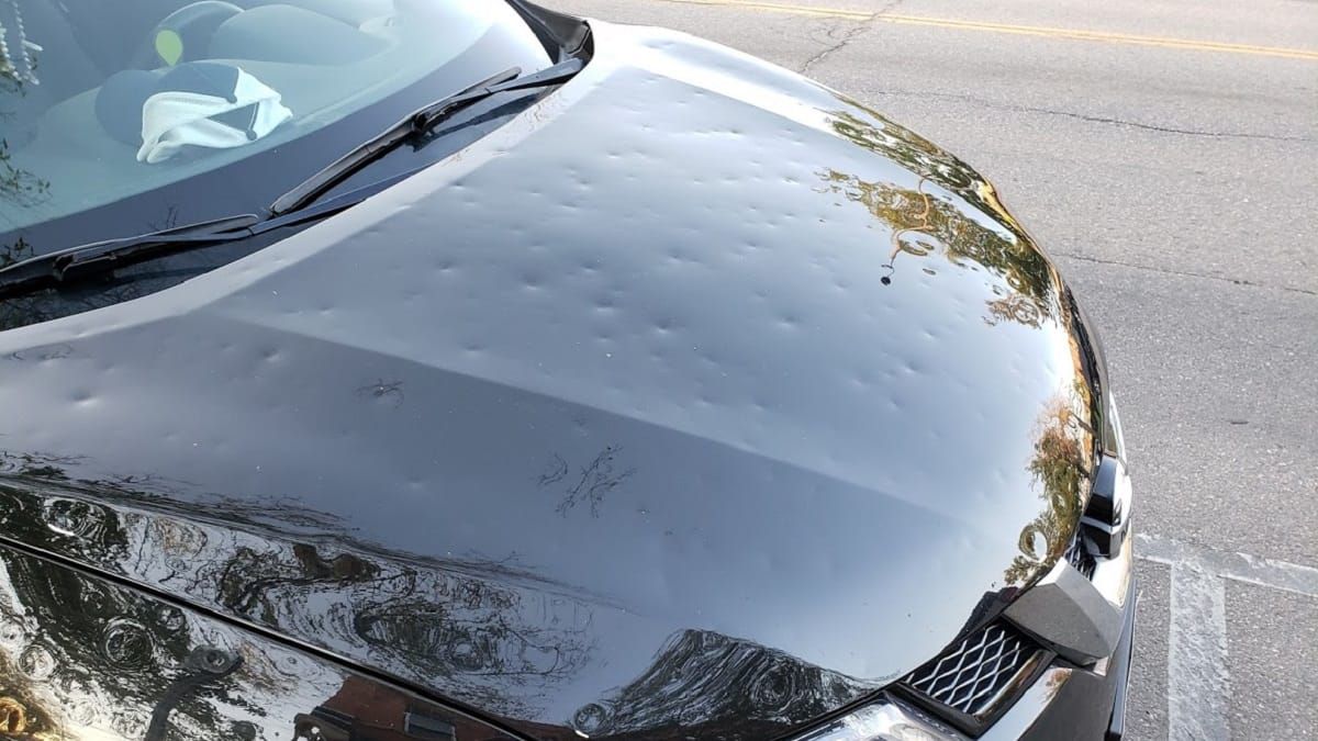 Heavy hail damage across the hood of a Nissan Sentra