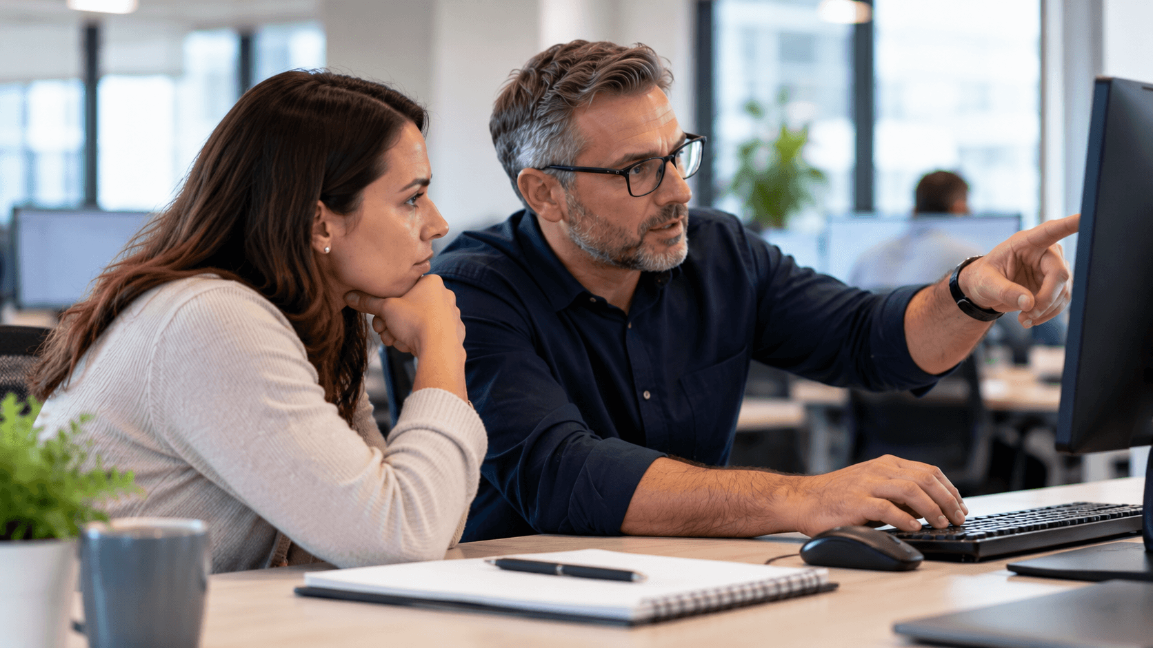 Two colleagues reviewing information on a computer while investigating an IT issue.