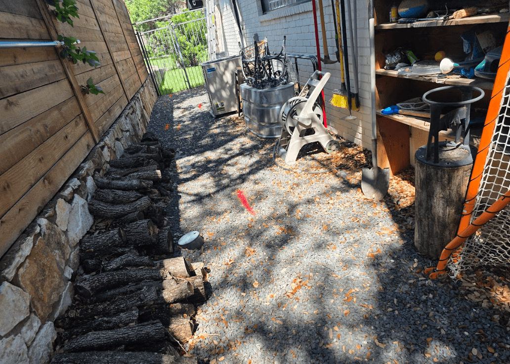 Utility locating markings in a narrow gravel side yard in Austin, TX showing electric and communication paths