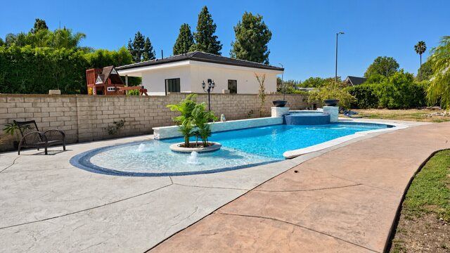 Freeform pool with a shallow shelf, palm island, raised spa and fire bowls