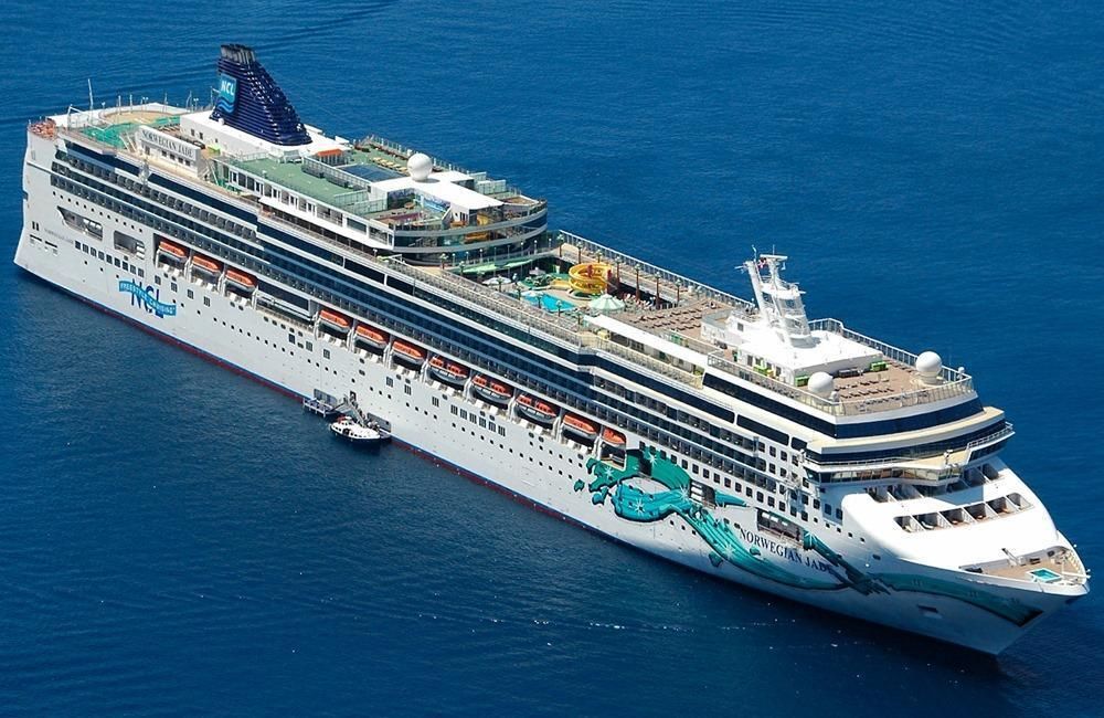 Norwegian Jade cruise ship sailing through deep blue water, with colorful hull artwork and open-air decks visible.