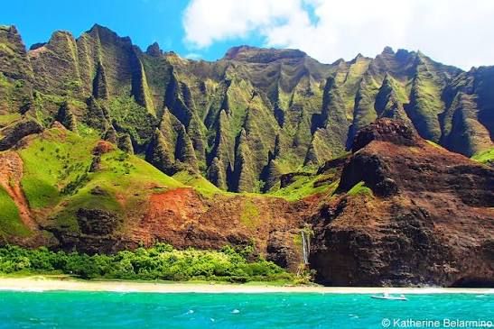 Towering emerald-green cliffs of Kauai's Nā Pali Coast rise dramatically above a secluded white-sand beach and turquoise Pacific Ocean, showcasing one of Hawaii's most breathtaking natural landscapes. Towering emerald-green cliffs of Kauai's Nā Pali Coast rise dramatically above a secluded white-sand beach and turquoise Pacific Ocean, showcasing one of Hawaii's most breathtaking natural landscapes.