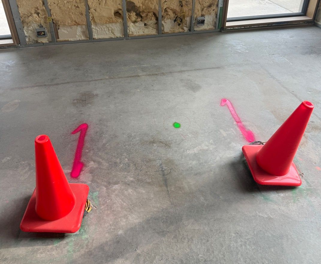 Marked concrete slab with cones flagging rebar and conduit before coring