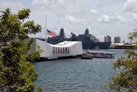 U.S.S. Arizona Memorial white building in harbor with flag flying at half-mast U.S.S. Arizona Memorial white building in harbor with flag flying at half-mast