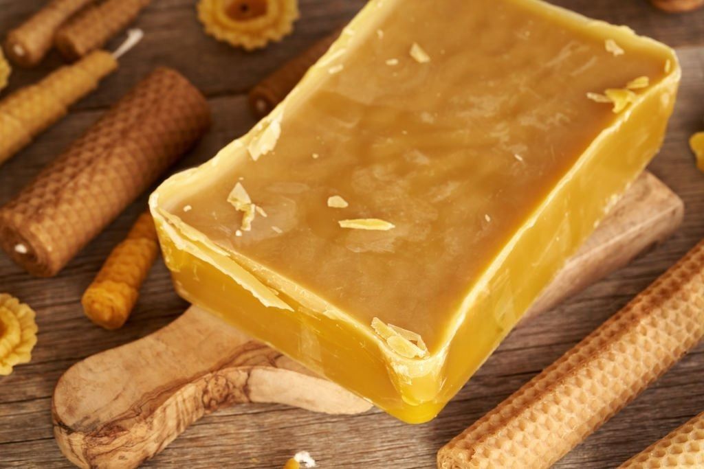 bloc de cire d'abeille posé sur une planche de bois et des bougies autour. bloc de cire d'abeille posé sur une planche de bois et des bougies autour.
