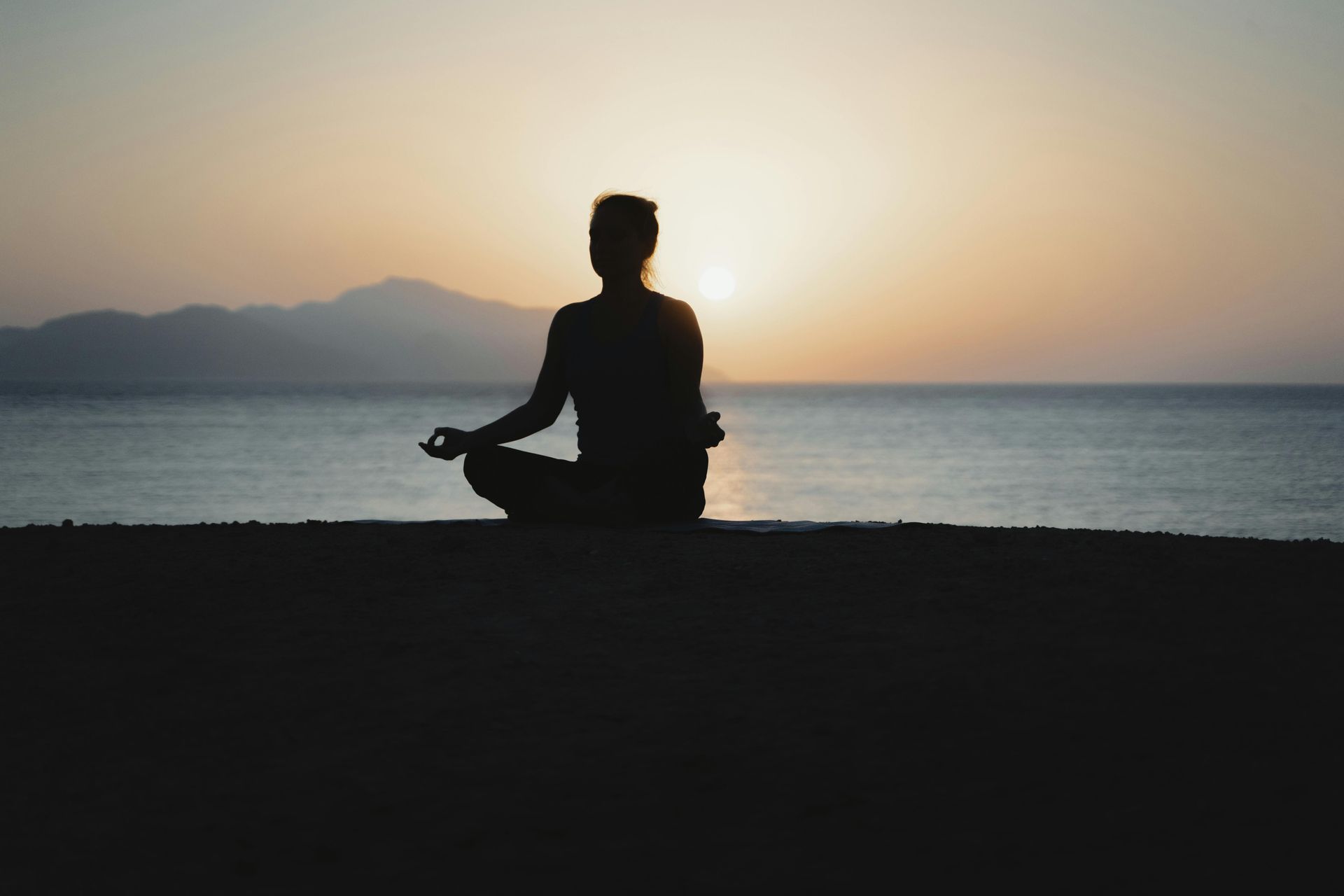 Diverse group of four people sitting in meditation circle with soft candlelight and natural window light