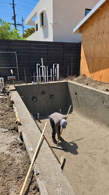 Crew member finishing a concrete pool shell during construction