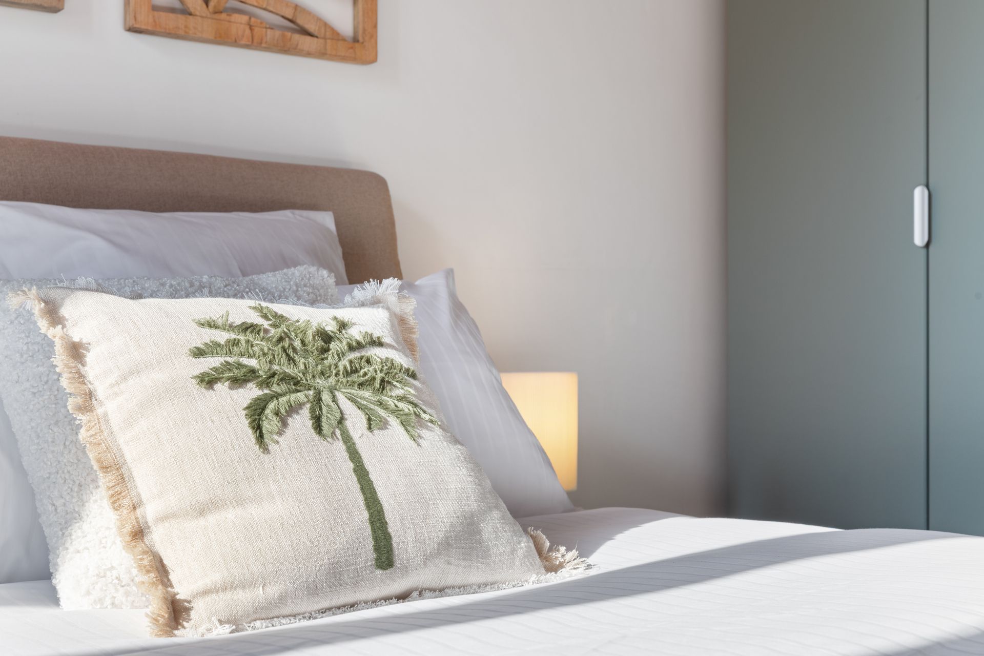 Chambre élégante de la Suite Tosca à Cannes, avec coussin palmier, lit queen-size et décoration Riviera.