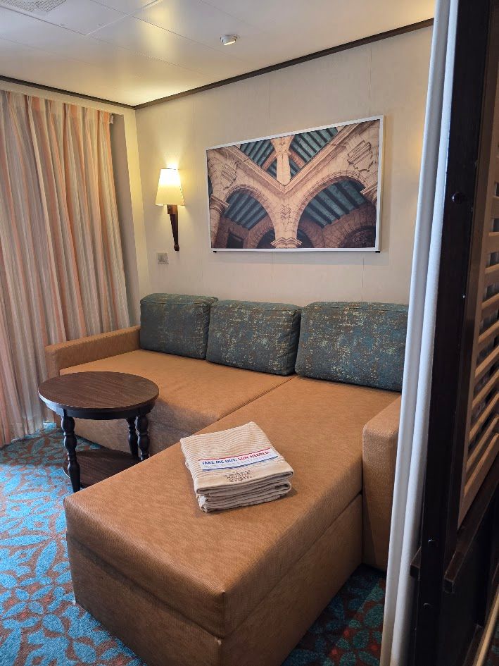 Modern Havana Cabana Suite with a cozy sofa, wall art, soft lighting, and a private balcony overlooking the ocean on a cruise ship. Modern Havana Cabana Suite with a cozy sofa, wall art, soft lighting, and a private balcony overlooking the ocean on a cruise ship.