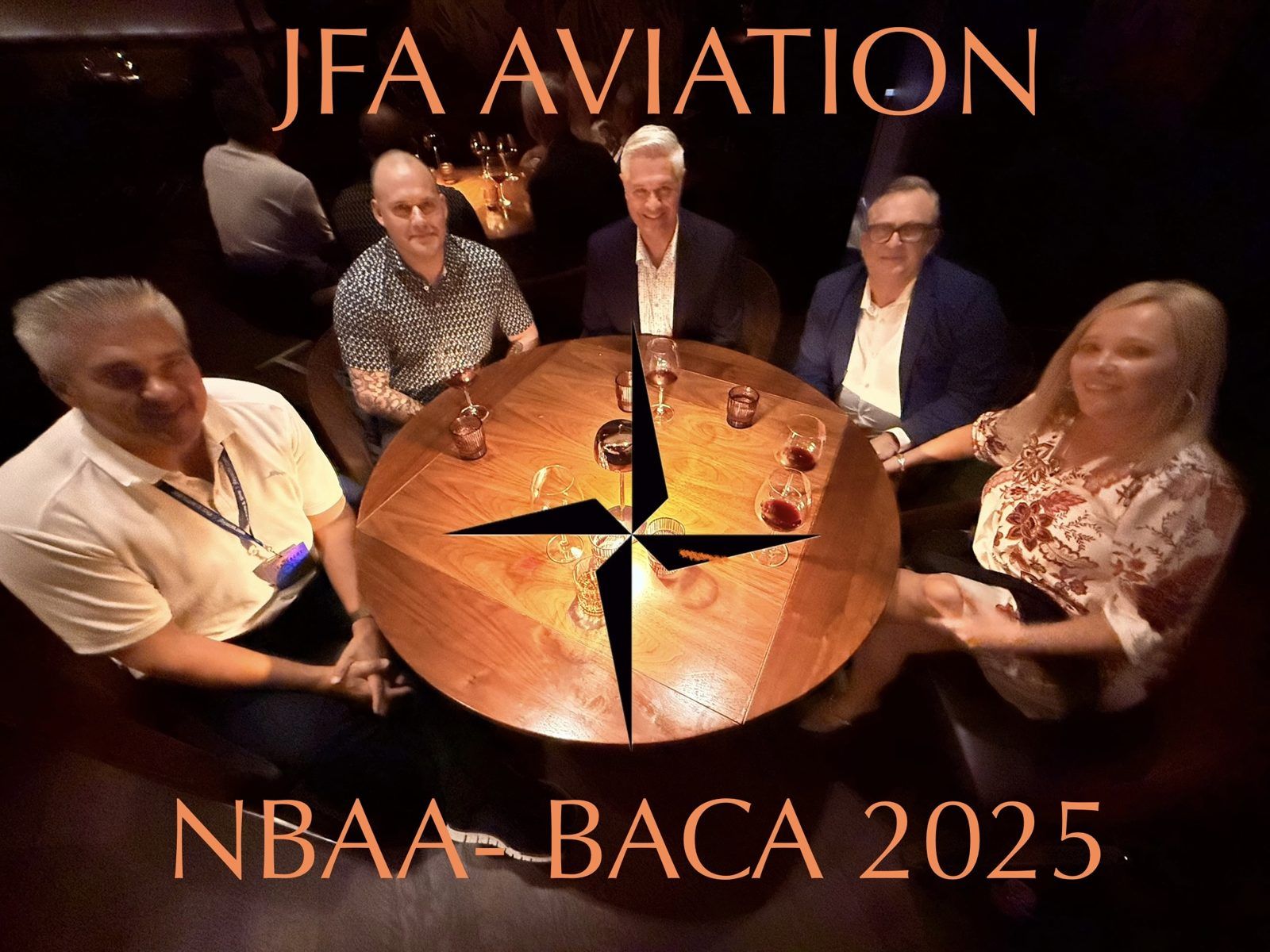 The five-person JFA Aviation team seated around a round dinner table, with a JFA Aviation graphic and compass mark overlaid