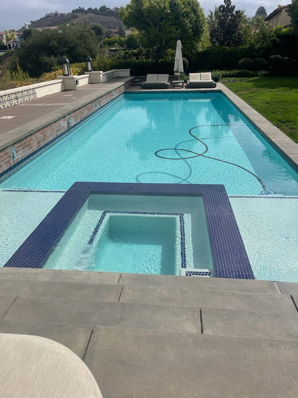 Refreshed swimming pool with integrated spa and dark tile border