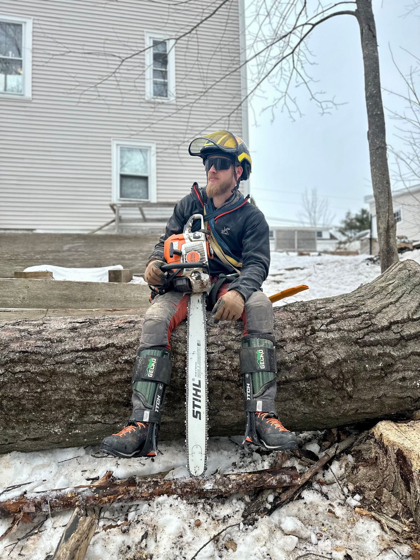 Arborist with a chainsaw on a log he just cut for tree service