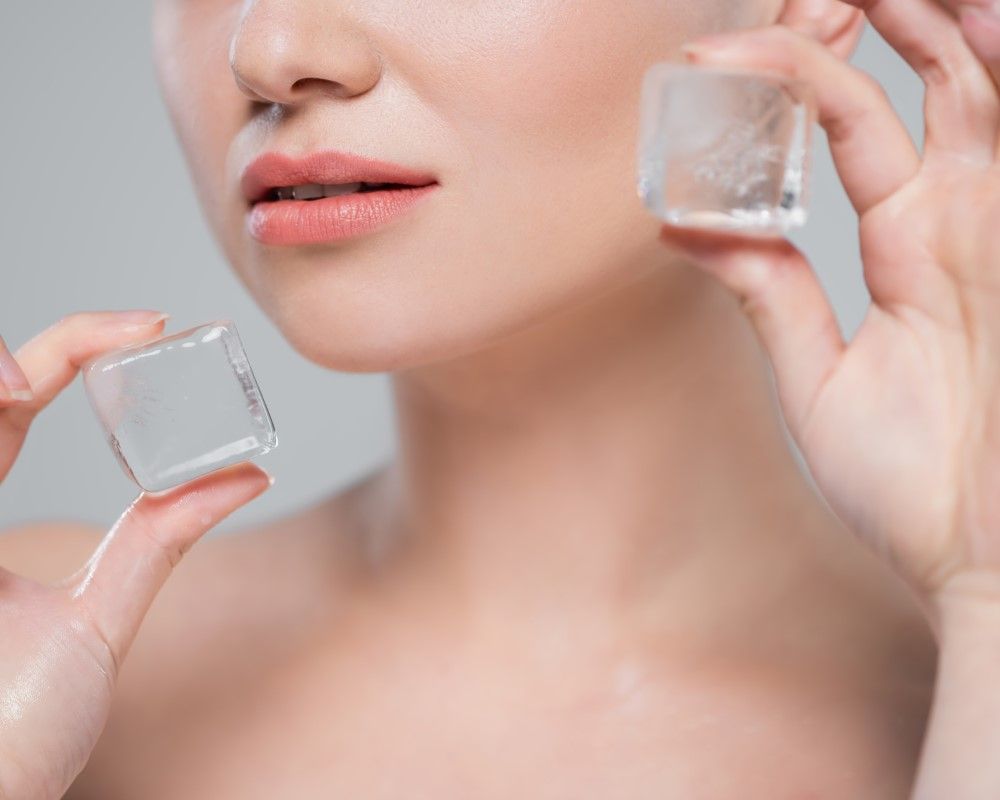 Foto de mujer sosteniendo hielo en sus mejillas para que le ayudan a obtener todos los beneficios de la bichectomía