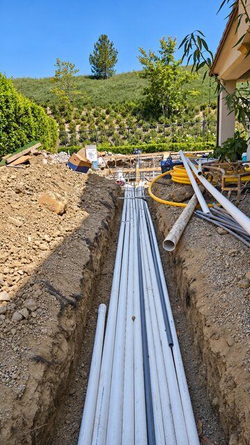 Pool plumbing lines installed in an open trench beside a patio
