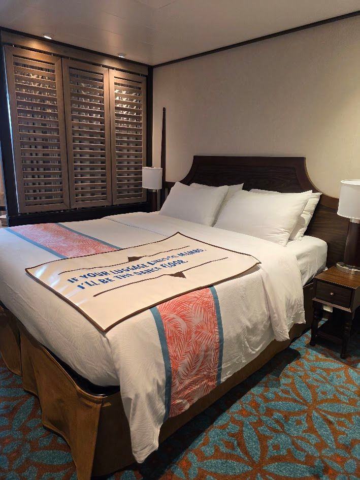 Cozy cruise ship bedroom with a large bed, soft lighting, modern decor, and a tropical-themed runner in a Havana Suite on Carnival Vista. Cozy cruise ship bedroom with a large bed, soft lighting, modern decor, and a tropical-themed runner in a Havana Suite on Carnival Vista.