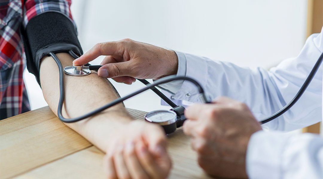 A doctor checking a patient’s blood pressure with a stethoscope and cuff during a medical examination at a clinic. A doctor checking a patient’s blood pressure with a stethoscope and cuff during a medical examination at a clinic.