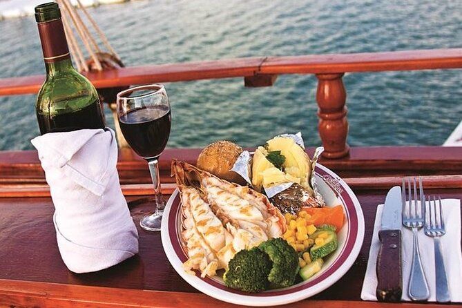 Plate of lobster, vegetables, and wine on a boat at sunset
