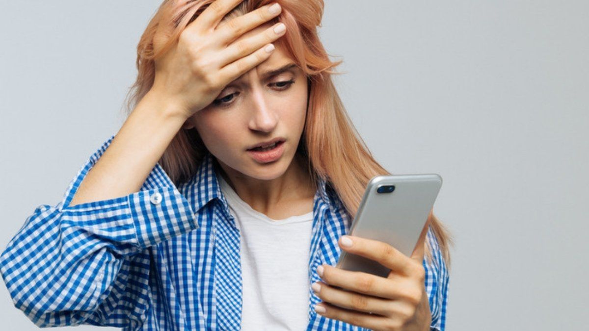 Woman looking worried at a phishing text message on her phone, a near-miss phishing attempt