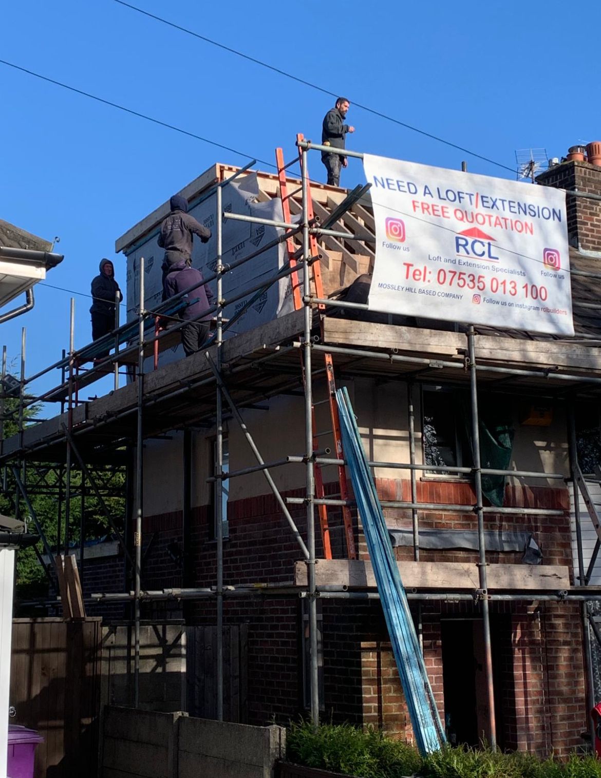 Roofing contractors installing asphalt shingles on residential home roof with safety equipment in bright daylight Roofing contractors installing asphalt shingles on residential home roof with safety equipment in bright daylight