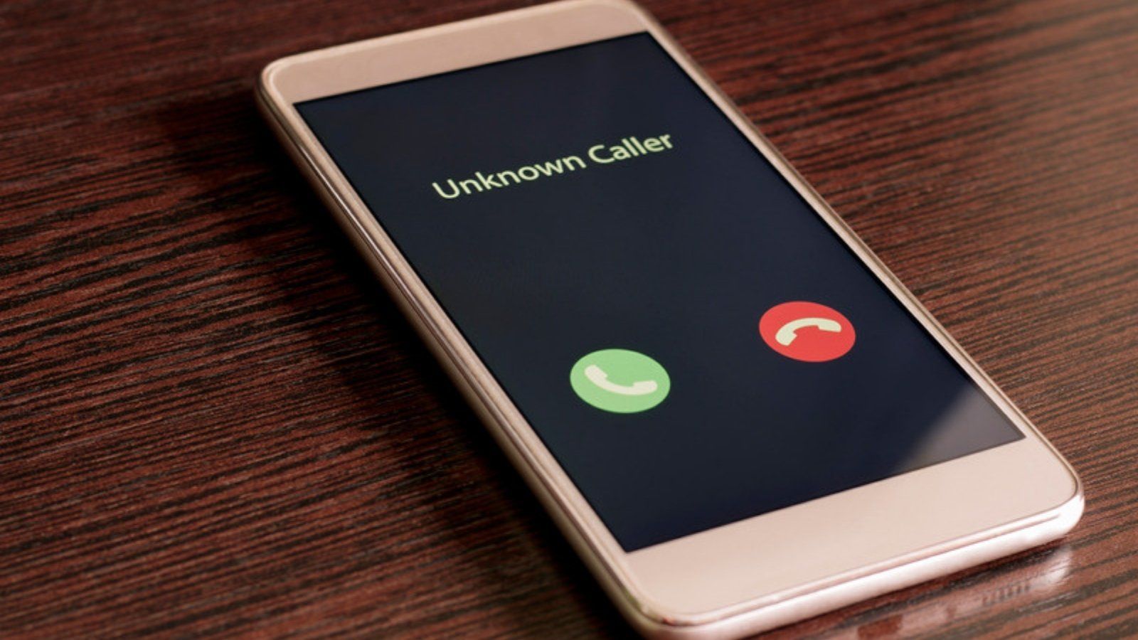Smartphone showing an unknown caller, a reminder to report and block scam text message senders