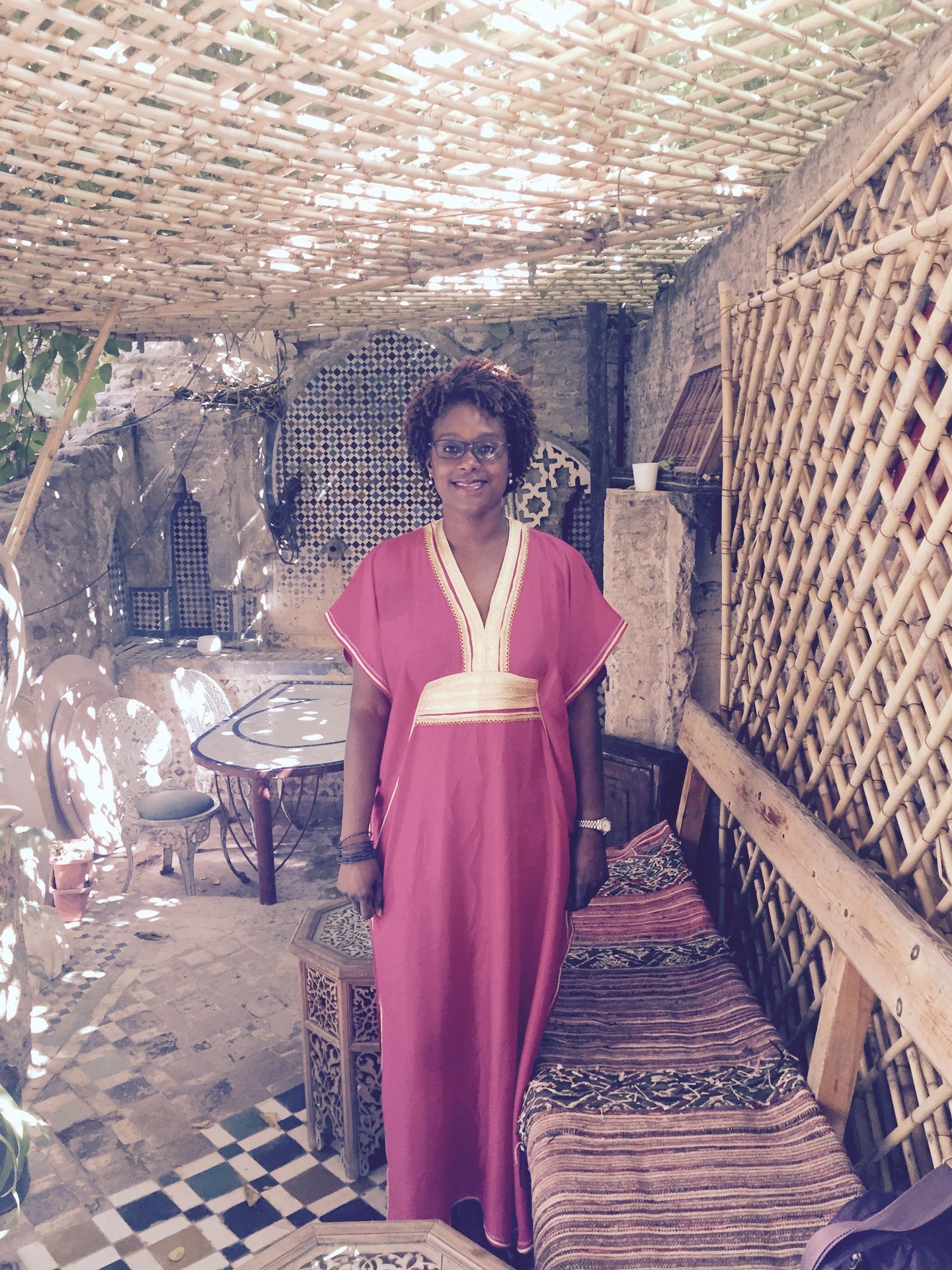 Michelle is wearing a fuschia kaftan while standing on a terrace at her riad in Fès, Morocco.