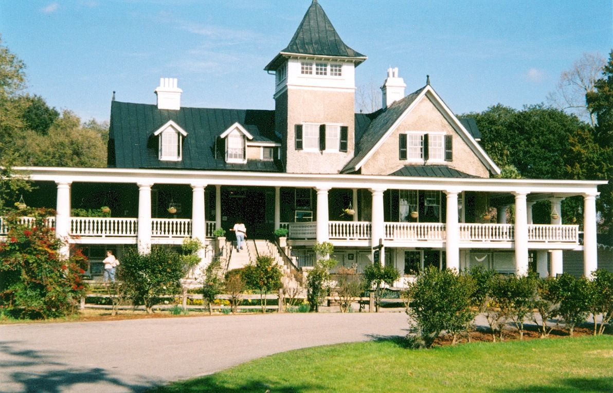 Historic Southern plantation house with white columns, wraparound porch, and landscaped gardens under a blue sky. Historic Southern plantation house with white columns, wraparound porch, and landscaped gardens under a blue sky.