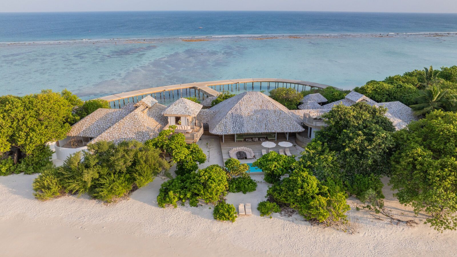 This image shows a arge beach villa surrounded by lust vegetation in indian ocean.