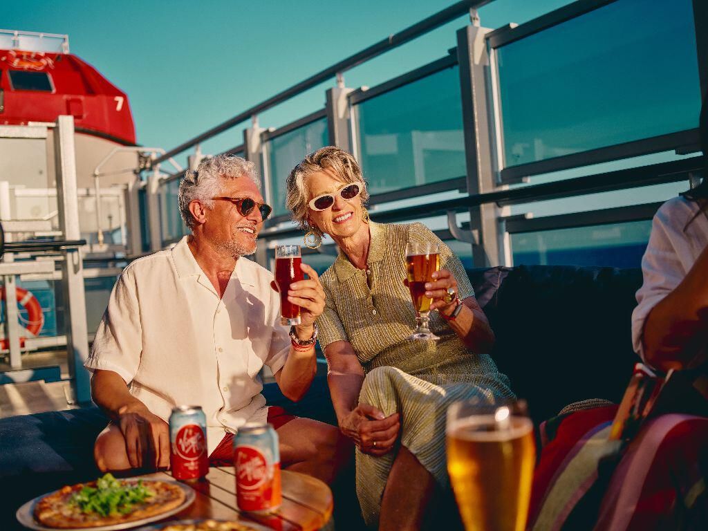 Smiling older couple enjoying drinks on a cruise ship deck. Smiling older couple enjoying drinks on a cruise ship deck.