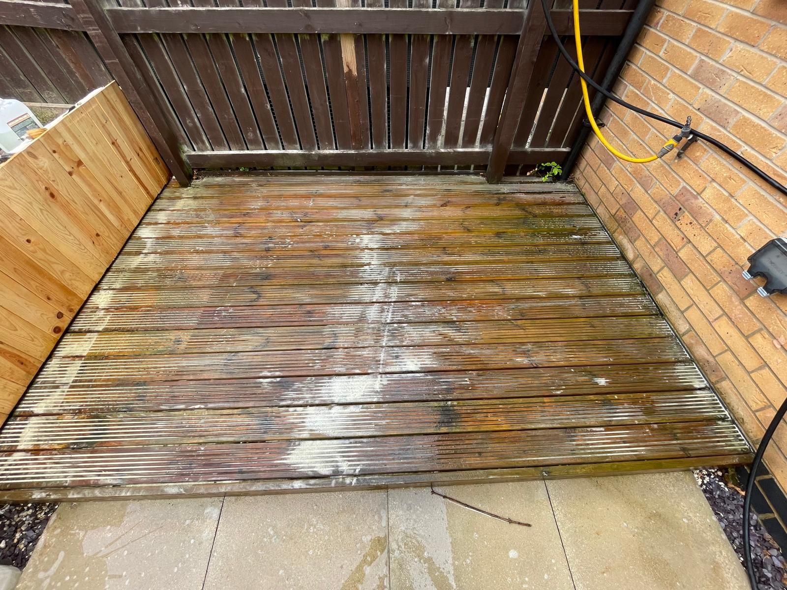 Softwood decking being cleaned, currently with a oil stripper on it
