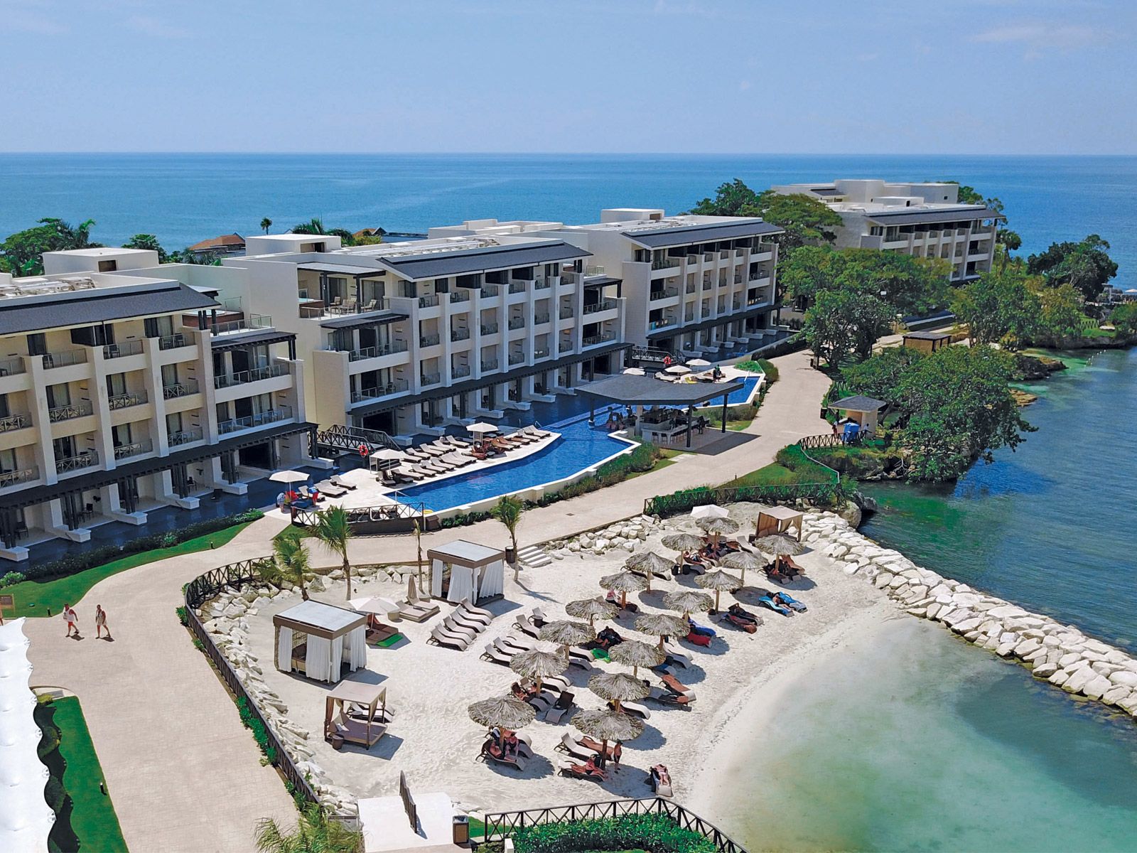 Aerial view of Hideaway at Royalton Negril in Jamaica featuring modern oceanfront suites, a beachfront infinity pool, private cabanas, white sand beach, and turquoise Caribbean waters.