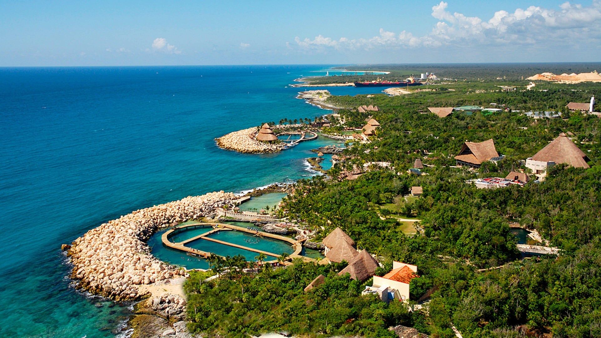 Aerial view of Xcaret Park with lush jungle, natural inlets, and the turquoise Caribbean Sea along the Riviera Maya coastline.