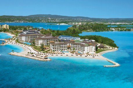 Aerial view of Secrets Wild Orchid resort in Montego Bay, Jamaica, featuring beachfront buildings, white sand, and bright turquoise Caribbean waters.