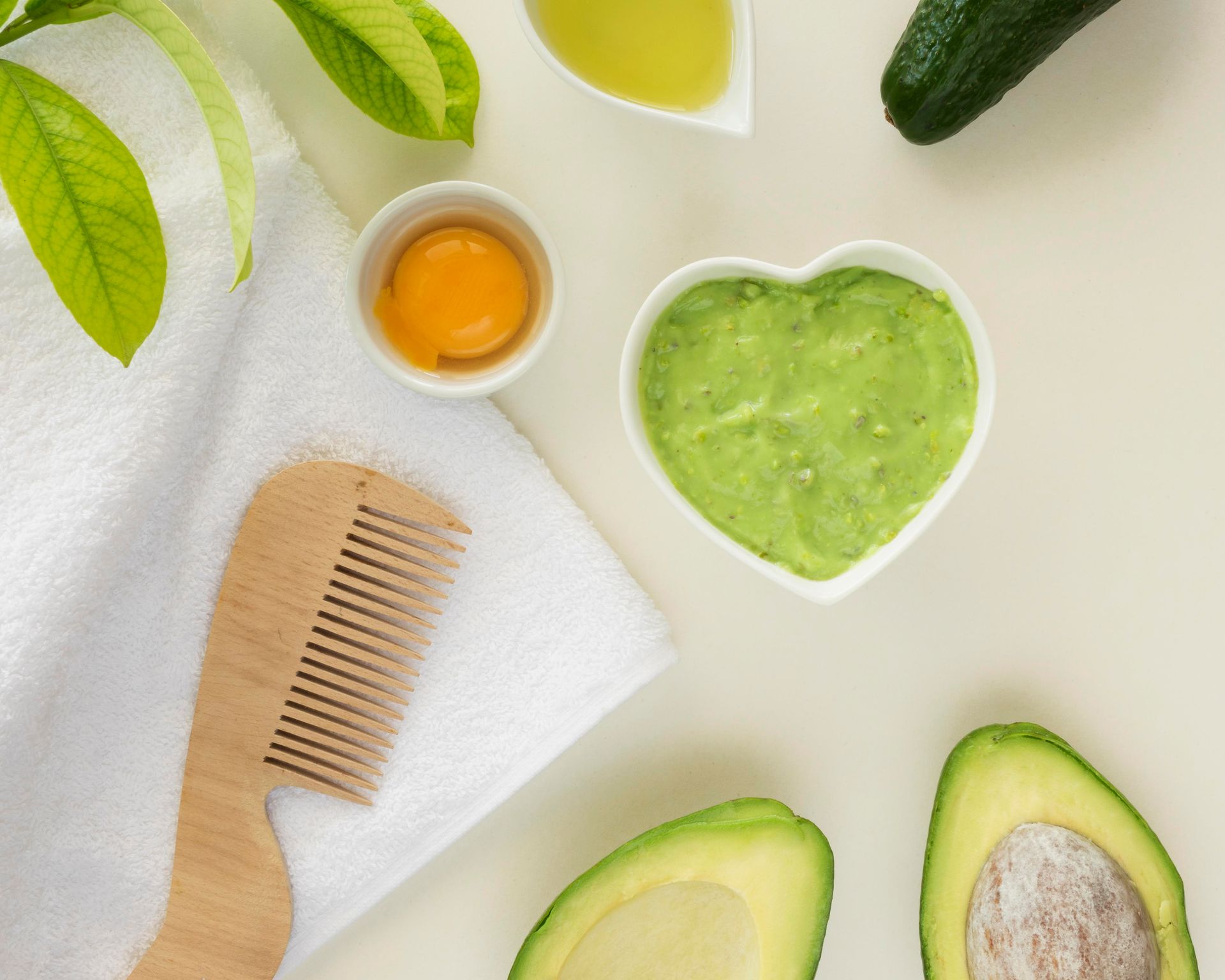 Un avocat, de l'huile d'avocat et un peigne disposés ensemble sur une table.