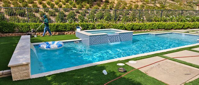 Pool with raised patterned tile spa, water feature, turf and concrete terrace