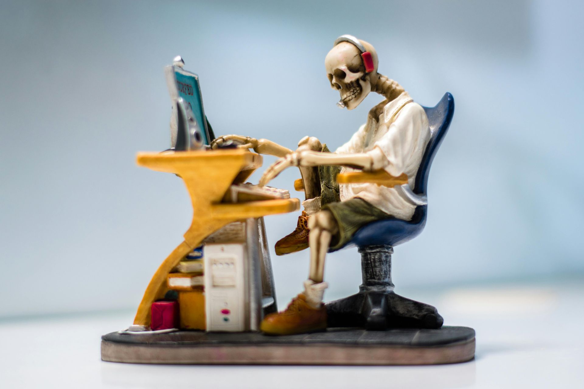 Skeleton sitting at a desk with a computer, symbolizing the relentless hours and exhaustion of managing a side hustle while balancing life's chaos