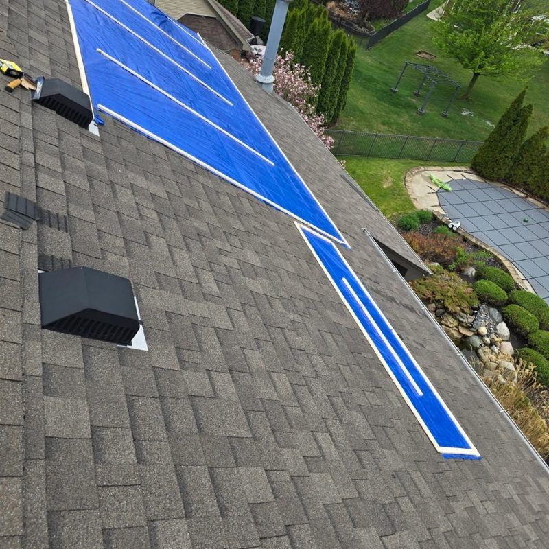 Blue emergency tarp secured on a shingle roof