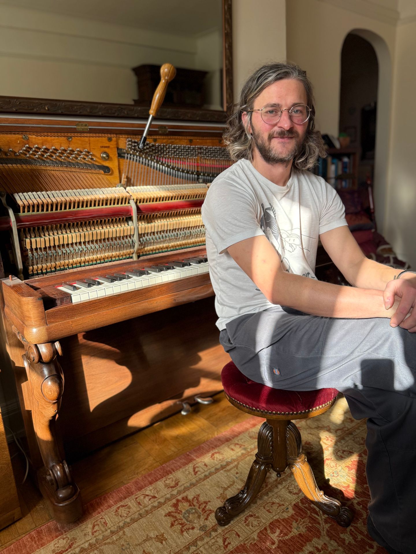 Piano Tuner Sitting next to a Steinway Piano right after tuning the instrument Piano Tuner Sitting next to a Steinway Piano right after tuning the instrument