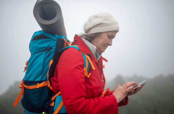 older woman with backpack looking at her phone
