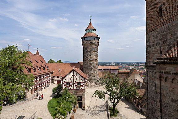 View of Nuremberg Castle with its stone tower, historic half-timbered buildings, and cobblestone pathways overlooking the old town of Nuremberg, Germany.
