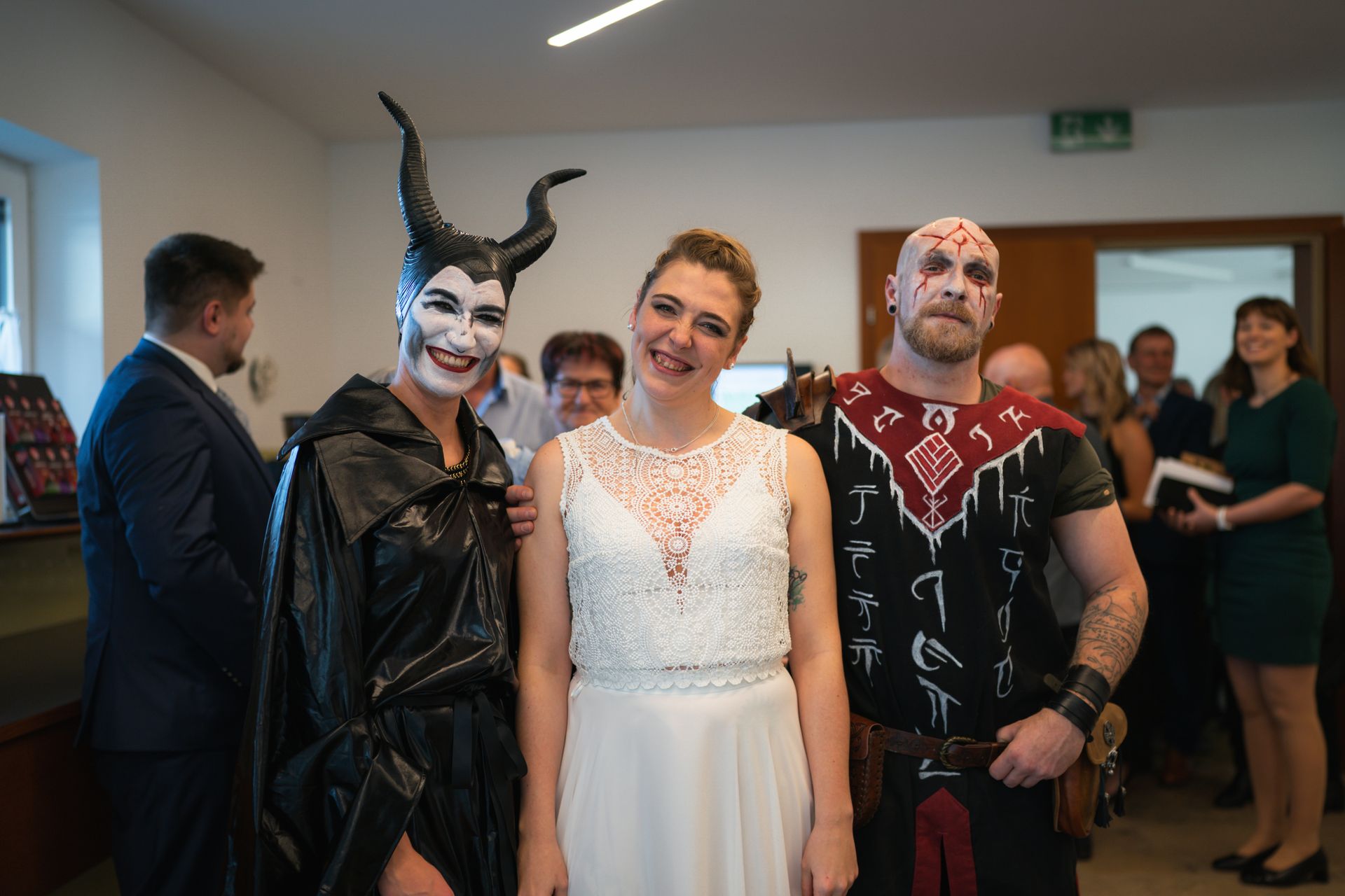 Braut posiert lĂ€chelnd mit zwei verkleideten GĂ€sten bei einer Halloween-Mottohochzeit im Landhotel Schicklberg; kreative KostĂŒme und festliche Stimmung. Braut posiert lĂ€chelnd mit zwei verkleideten GĂ€sten bei einer Halloween-Mottohochzeit im Landhotel Schicklberg; kreative KostĂŒme und festliche Stimmung.