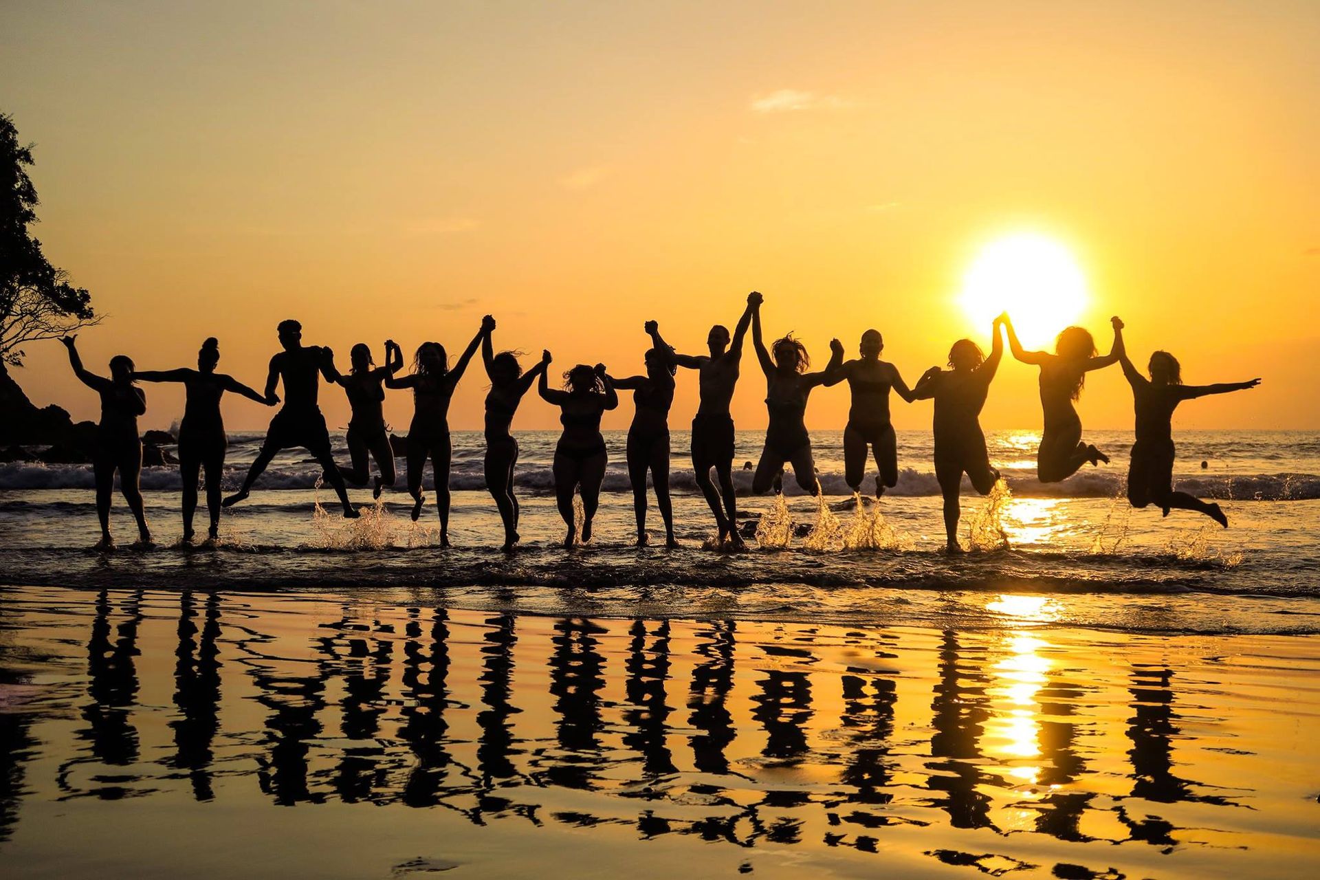 Travelers leap in the ocean at sunset, silhouetted against a golden sky, capturing the excitement and connection of a guided group vacation. Travelers leap in the ocean at sunset, silhouetted against a golden sky, capturing the excitement and connection of a guided group vacation.