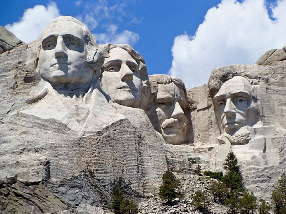 Mount Rushmore National Memorial featuring the carved faces of Presidents George Washington, Thomas Jefferson, Theodore Roosevelt, and Abraham Lincoln under a bright blue sky. Mount Rushmore National Memorial featuring the carved faces of Presidents George Washington, Thomas Jefferson, Theodore Roosevelt, and Abraham Lincoln under a bright blue sky.