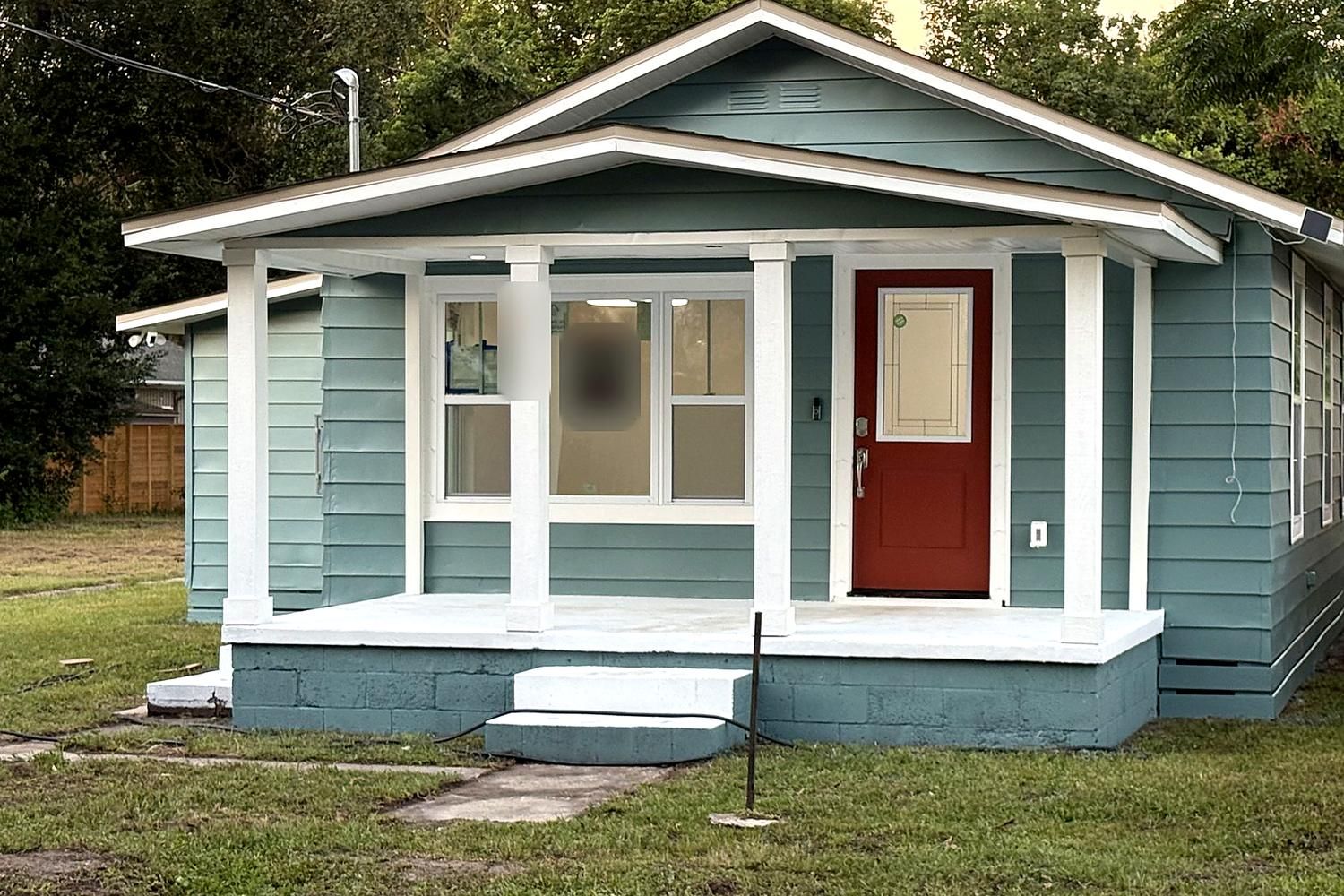 Renovated teal craftsman cottage with a new white front porch and red door
