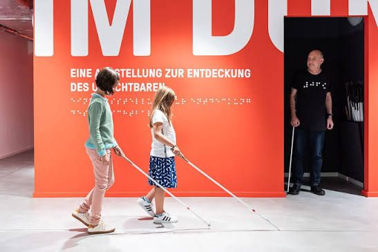 Visitors explore the Dialog Museum in Frankfurt, Germany, using white canes during a guided experience in complete darkness that helps guests understand life from the perspective of someone who is blind.
