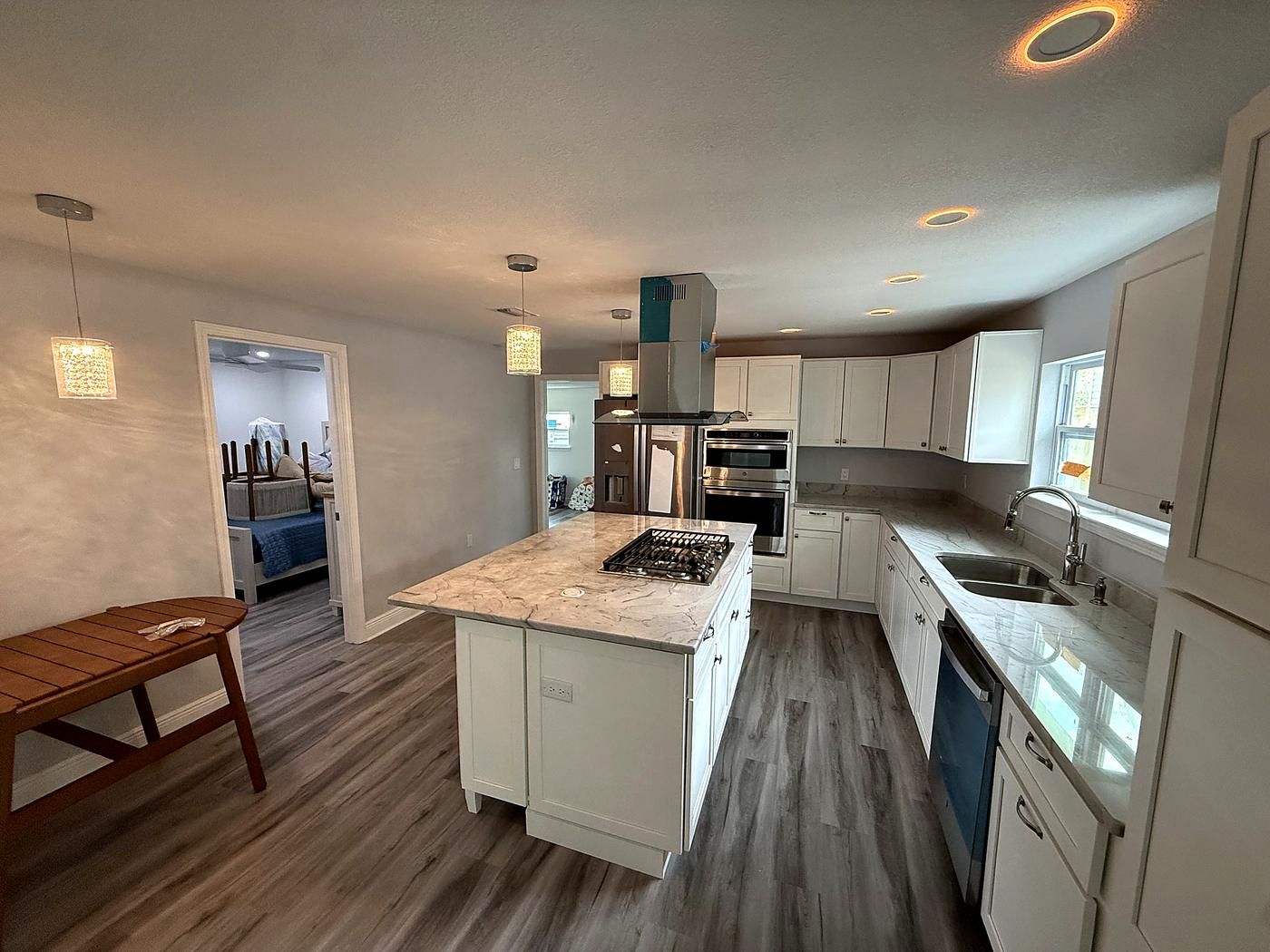 Renovated kitchen with white shaker cabinets, an island cooktop and pendant lights
