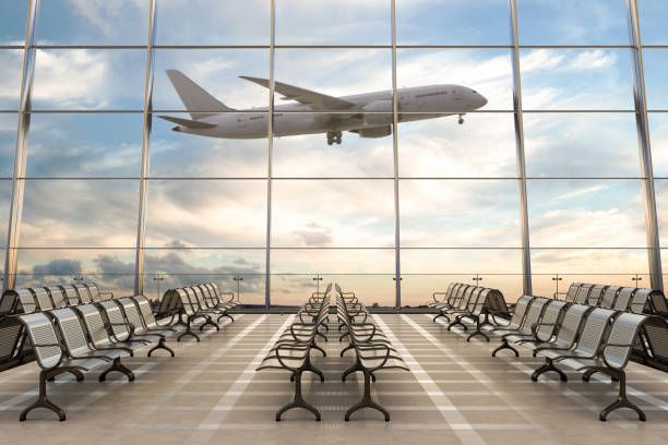 Airplane taking off outside large airport windows with empty rows of seats in the terminal.