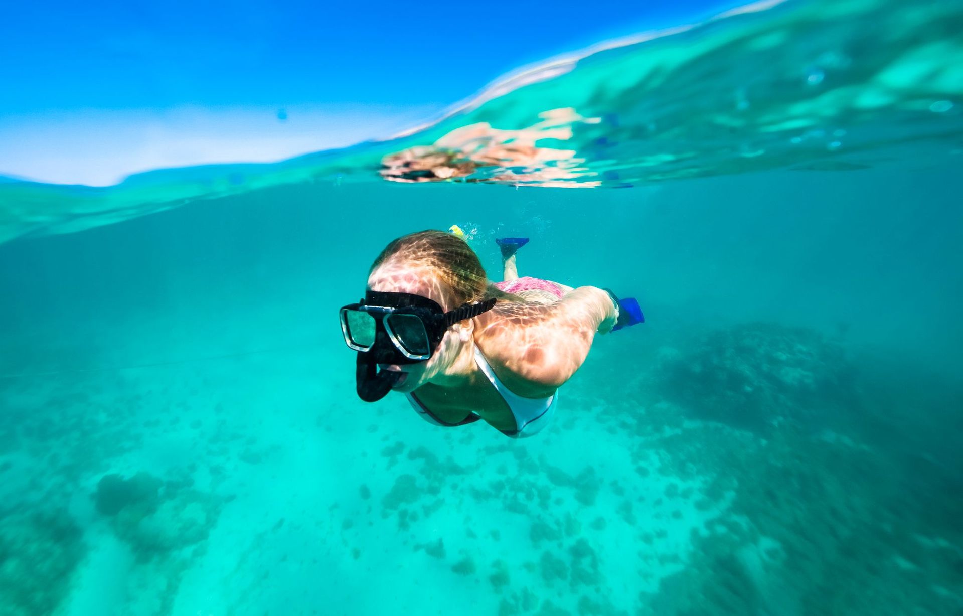 Traveler snorkeling in clear turquoise water, exploring coral reefs under the surface on a sunny day in Saint Lucia.