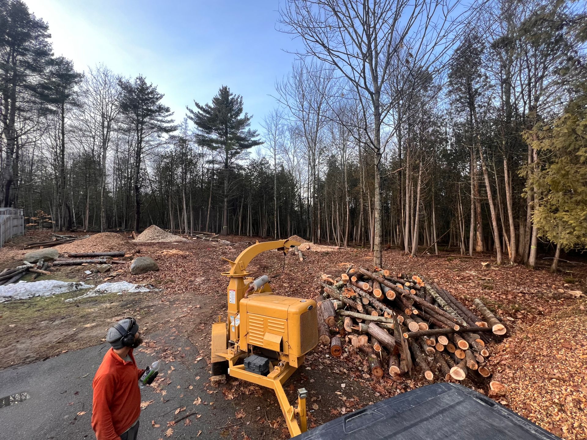 Well Rounded Tree Service crew operating a wood chipper during a land clearing project in Central Maine, processing cut logs and branches for efficient site cleanup.