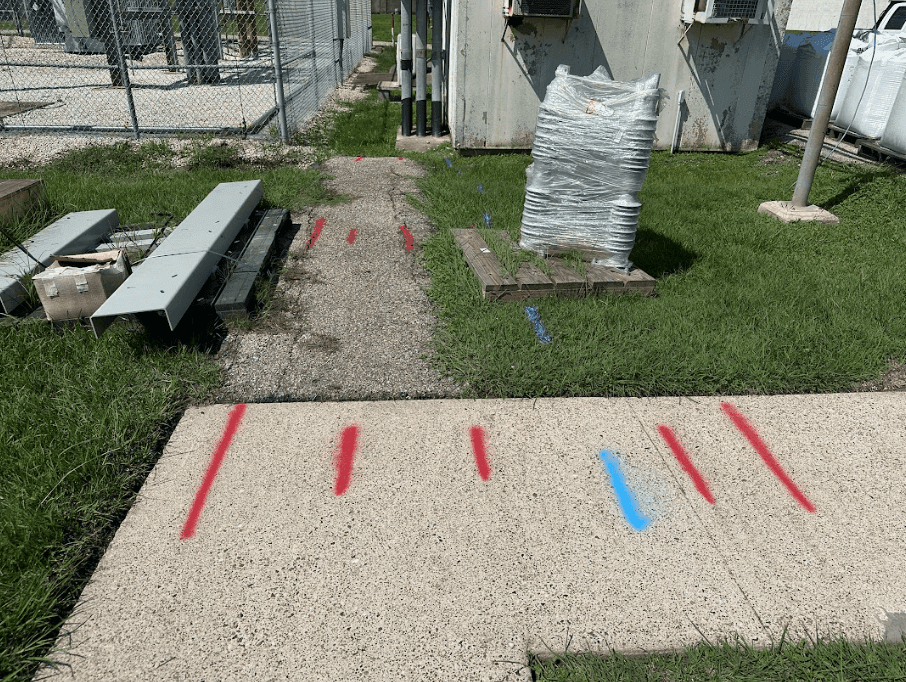 Red and blue utility locate marks painted across a concrete sidewalk Red and blue utility locate marks painted across a concrete sidewalk