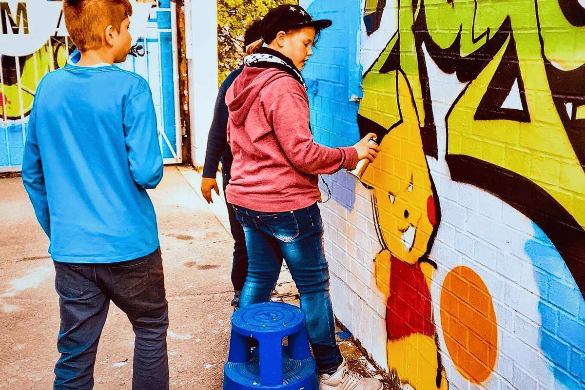 Teilnehmendes Kind sprayt eigenständig beim Urban Art Workshop im Jugendhaus Stuttgart-Feuerbach ein selbst entwickeltes Graffiti-Motiv